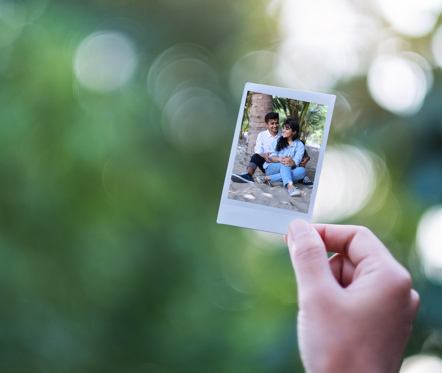 A Polaroid-style magnet featuring a scenic photo, held by a hand outdoors against a blurred greenery backdrop.